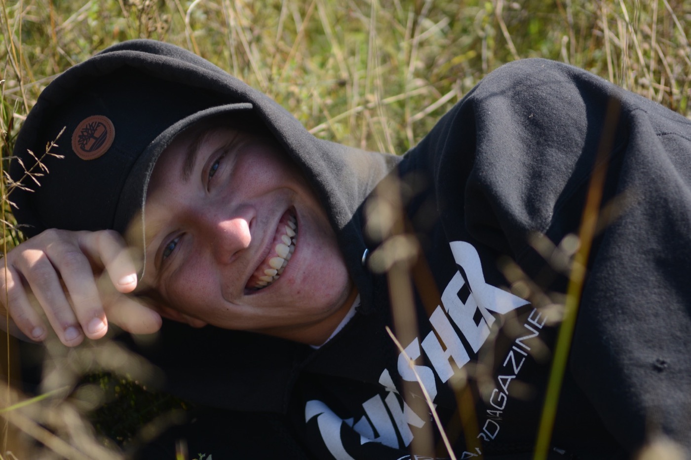 Dameon Spencer smiling while lying in tall grass